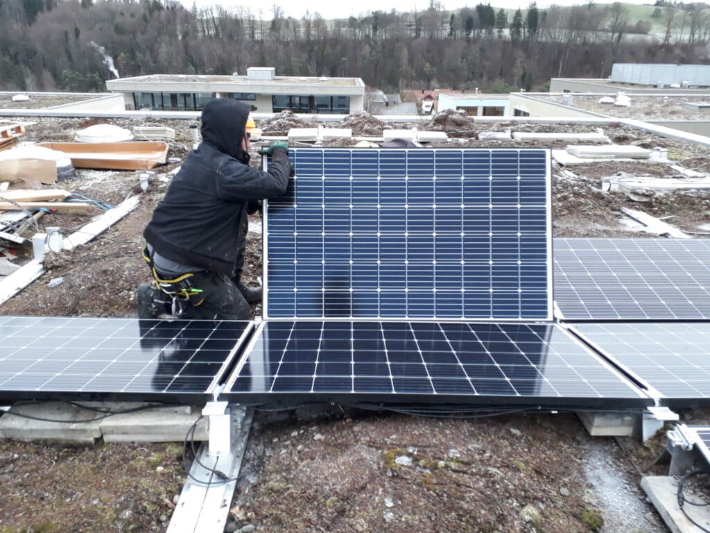 Ein Techniker installiert Solarpanels auf einem Flachdach, umweltfreundliche Energiegewinnung durch Photovoltaik.